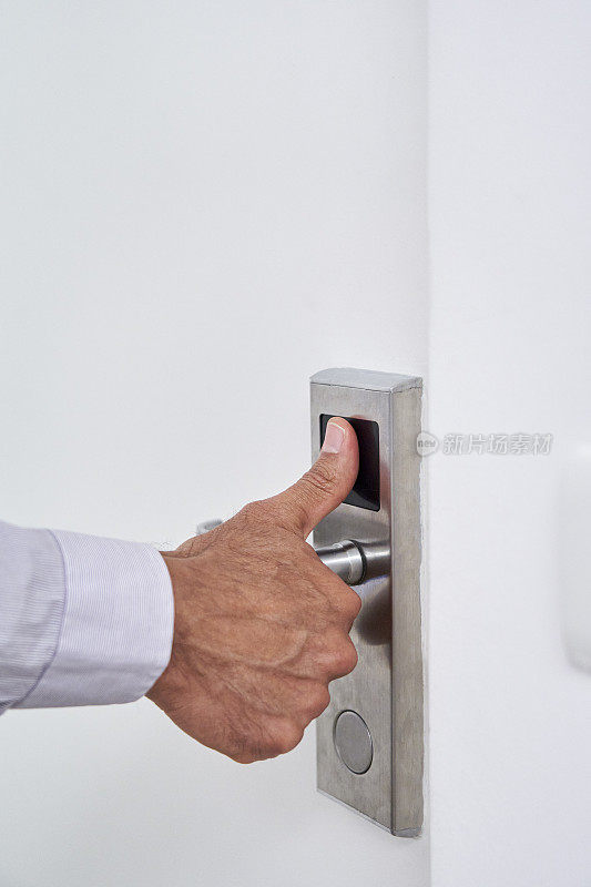 Man placing thumb on fingerprint-reading door lock